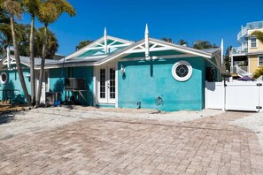 Una casa con pareti color acquamarina, una porta bianca e una piccola finestra circolare.