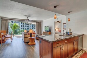 Ein modernes Hotelzimmer mit Kücheninsel, Essbereich und einem Balkon mit Stadtblick.
