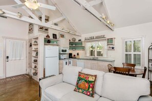 A kitchen with white cabinets, a refrigerator, a microwave, and a dining area with a table and chairs. - Silver House | 2/2, Pet Friendly w/ fee (Fredericksburg)