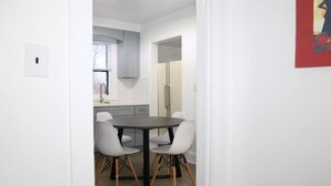 A modern kitchen with white cabinets, a dark countertop, and a dining area with a table and chairs.