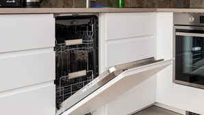 Una cocina moderna con lavavajillas, horno y una encimera de mármol.