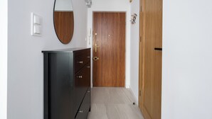 Un pasillo con una puerta de madera, un espejo, un armario negro y un interruptor de luz.