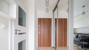 En modern inredning med en dörr i trä, en glasvägg och en matplats med en grå soffa och en stol.