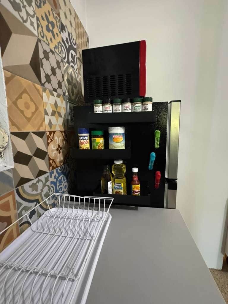 A kitchen with a black refrigerator, a white countertop, and a patterned backsplash.