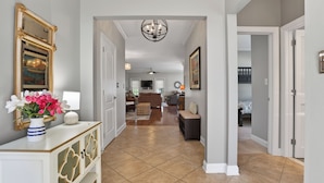 A hallway with a white console table, a mirror, and a vase of flowers. - One Level Rehoboth Beach House Steps to Pool (Rehoboth Beach)