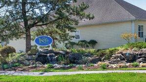 A hotel sign, a landscaped garden with rocks and plants, and a building with a tiled roof. - One Level Rehoboth Beach House Steps to Pool (Rehoboth Beach)