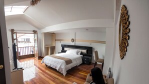 Ett hotellrum med en säng, en soffa, en TV och en balkong.
