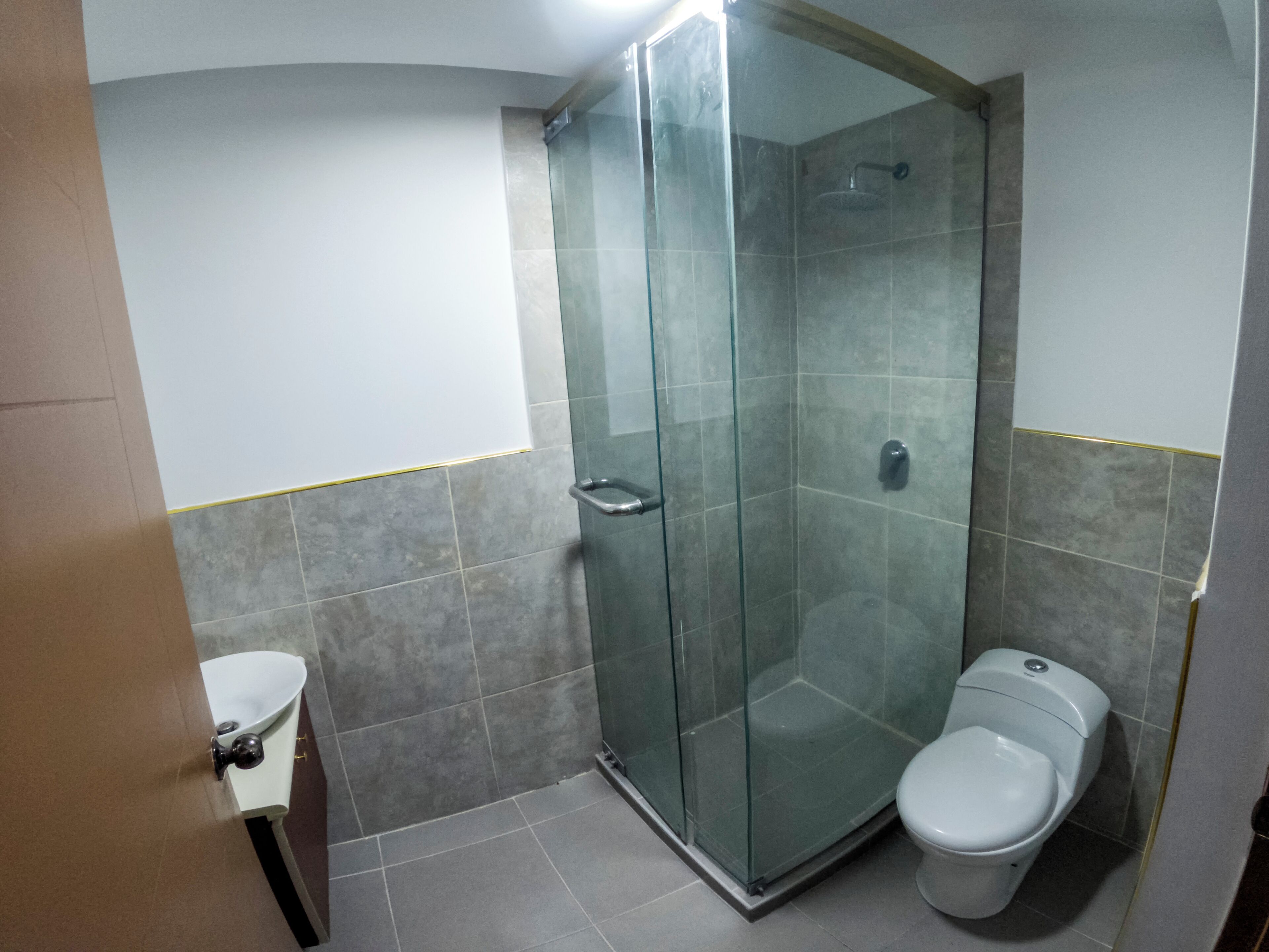 A bathroom with a glass shower enclosure, a toilet, and a sink.