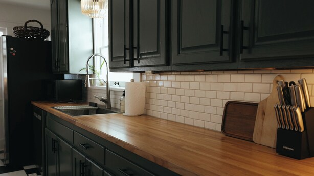 A kitchen with dark cabinets, a wooden countertop, a sink, a microwave, and a knife block. - Vintage Style Home Near Downtown | W&D + Patio (Wichita)