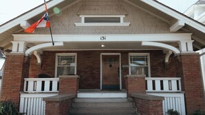 A brick house with a front porch, a wooden door, and a flag. - Vintage Style Home Near Downtown | W&D + Patio (Wichita)