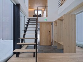 Un intérieur moderne avec un escalier en bois, une porte portant un panneau indiquant la sortie de secours et un banc.