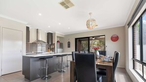 Una cocina moderna con una isla central, taburetes de bar y un comedor con mesa y sillas.