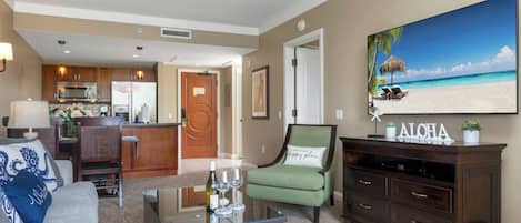 A living room with a sofa, a coffee table, a TV, and a painting of a beach.