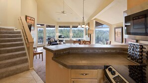 Una cocina con una isla grande, un comedor con vistas y una escalera.