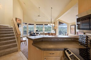 A kitchen with a large island, a dining area with a view, and a staircase. - River Ridge 429A- River views, hot tub 2bd 2 ba condo just 20 minutes from Mt Bachelor (Bend)
