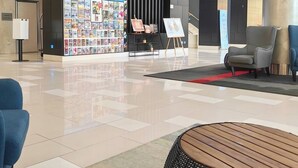 A modern lobby with a reception desk, a magazine rack, and a seating area with a round table and chairs. - Blue Bunny-Eared Stay | Ocean View | 2min to Beach (Surfers Paradise)