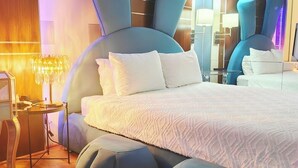 A modern bedroom with a large bed, round ottomans, a bedside table, and a mirror. - Blue Bunny-Eared Stay | Ocean View | 2min to Beach (Surfers Paradise)
