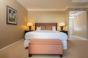 A hotel room with a large bed, two bedside tables with lamps, a framed picture on the wall, and a carpeted floor. - KBM Resorts | 4 FREE CARS | Honua Kai Hokulani | Ocean view | 7-Bedroom Multi-Unit Listing,  Recently Updated, Sunsets! ML-2957 (Lahaina)