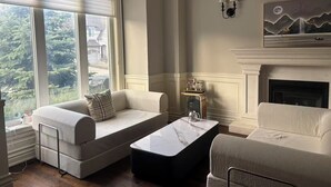 A living room with two sofas, a coffee table, a fireplace, and a painting on the wall. - Cozy Room 202 | Private Bathroom | Free Parking | Easy Transit (Toronto)