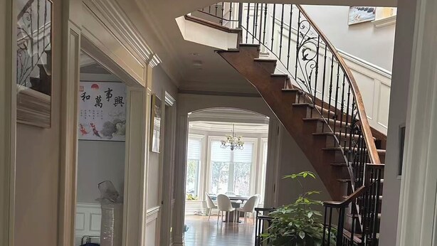 A spacious hallway with a wooden staircase, a chandelier, and a view into a dining area. - Cozy Room 202 | Private Bathroom | Free Parking | Easy Transit (Toronto)