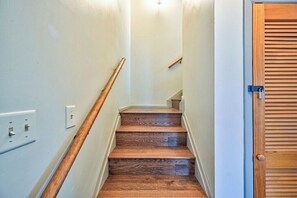 Un escalier avec des marches en bois et une rampe, menant à une porte ornée de panneaux en bois.