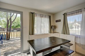 A room with a wooden table, white bench seating, a view of the outdoors, and a sign on the wall. - The Cottage on Colorado (Buena Vista)