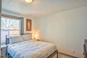 Quarto com uma cama, mesa de cabeceira, luminária e janela.