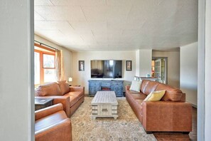 Ein Wohnzimmer mit zwei Sofas, einem Couchtisch und einem Flachbildfernseher.