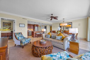 A spacious living room with a sofa, armchairs, a coffee table, and a dining area with a kitchen in the background. - 3 Honua Kai Villas | Ocean Front | Sleeps 24 | Free Car w/ 6+ Nights | ML-3041 (Lahaina)