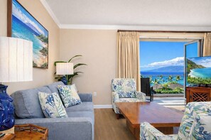 A living room with a sofa, armchairs, a coffee table, and a TV. There is a large window with a view of the ocean. - Honua Kai | Ocean View 8 BR, Sleeps 24 | Car Incl. w/ 6+ Nights | HKH ML-3041 by KBM (Lahaina)