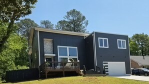 Une maison à deux étages avec une terrasse, un garage et un jardin devant.