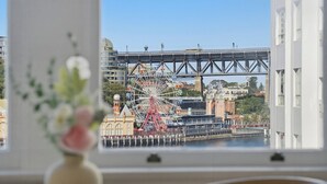 Vista de una noria y un puente desde una ventana, con un florero sobre la mesa.