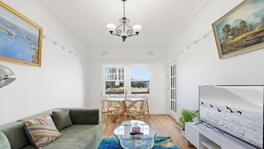 Una sala de estar con sofá, una mesa de centro de vidrio, televisor y un comedor con sillas y mesa.