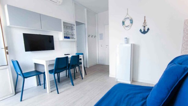 Et lille værelse med seng, skrivebord med stole, TV og køleskab.