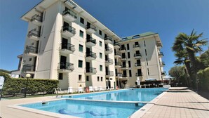 Et hotel med flere etager, en swimmingpool, altaner og en klar himmel.