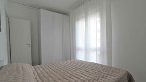 Une chambre à coucher avec un lit, une porte et des rideaux légers.