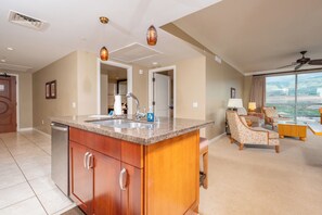 A modern hotel room with a kitchen island, a dining area, and a view of the outdoors. - 2 Honua Kai Villas | Ocean Front | Sleeps 14 | Free Car w/ 6+ Nights | ML-3074 (Lahaina)