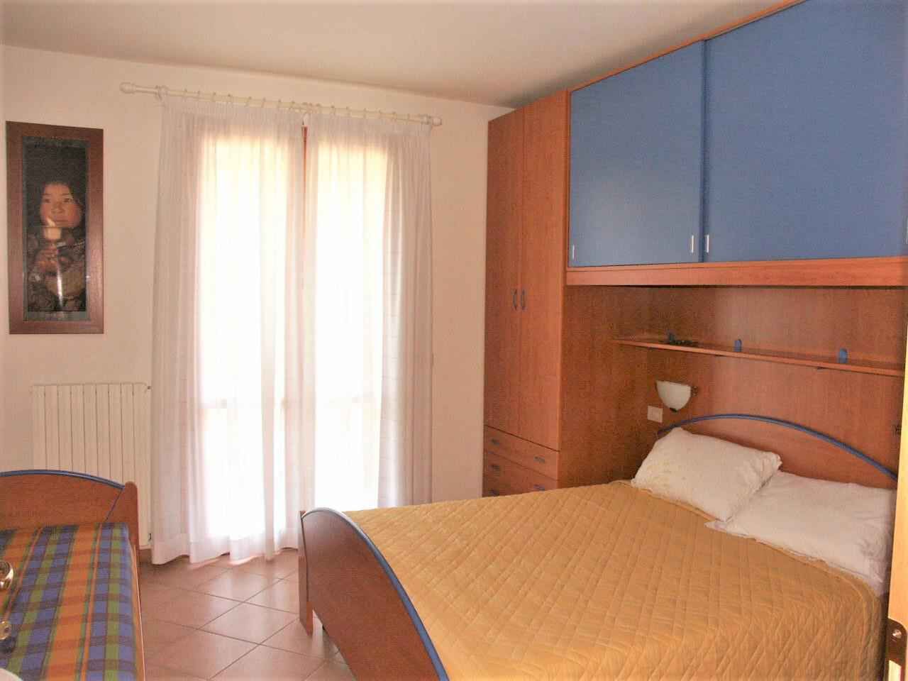 Een slaapkamer met een bed, een houten garderobe, een raam met gordijnen en een radiator.