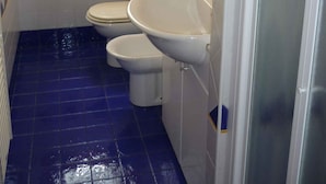 Een badkamer met twee toiletten, een wastafel en een raam.