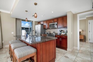 A modern kitchen with a central island, stainless steel appliances, and wooden cabinets. - Honua Kai | Ocean View 4 BR, Sleeps 12 | Car Incl. w/ 6+ Nights | HKH ML-3077 by KBM (Lahaina)