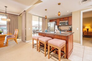 A modern kitchen with a central island, wooden cabinets, and stainless steel appliances. - 2 Honua Kai Villas | Ocean Front | Sleeps 12 | Free Car w/ 6+ Nights | ML-3077 (Lahaina)