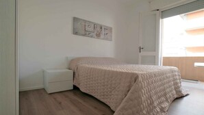 Camera da letto con un letto, un comodino, un'opera d'arte a parete e una porta scorrevole che dà su un balcone.