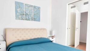 Ein Schlafzimmer mit einem Bett, einem Nachttisch, einer Lampe und einer Tür.