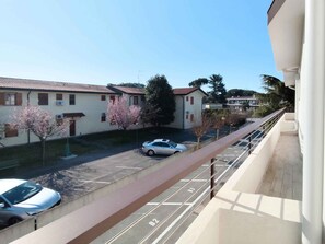 A residential area with a parking lot, a white car parked, and a building with a tiled roof. - Holiday apartment with balcony (Cavallino-Treporti)