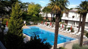 Ein Swimmingpool, umgeben von Palmen und weißen Liegestühlen.