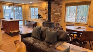 A cozy cabin interior with a wooden interior, a fireplace, a dining area, and a pet-friendly space.