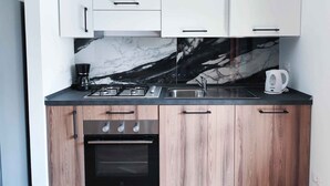 A modern kitchen with a gas stove, oven, and a coffee maker. - Holiday apartment with balcony (Cavallino-Treporti)