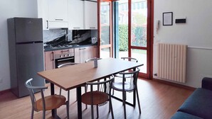 A modern kitchen with a refrigerator, stove, and dining table with chairs. - Holiday apartment with balcony (Cavallino-Treporti)