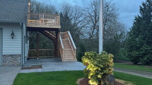 A two-story house with a wooden deck, a staircase, and a well-maintained lawn. - Moonstruck Studio: In Wine Country (Newberg)