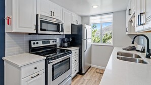 Una cocina moderna con armarios blancos, electrodomésticos de acero inoxidable y un ventanal con vistas al exterior.